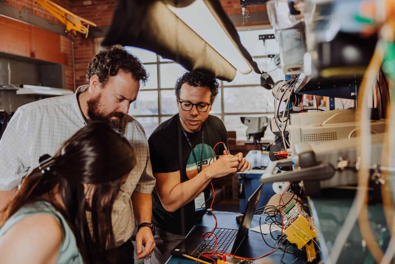 Three electronics engineers in the lab look at a project together