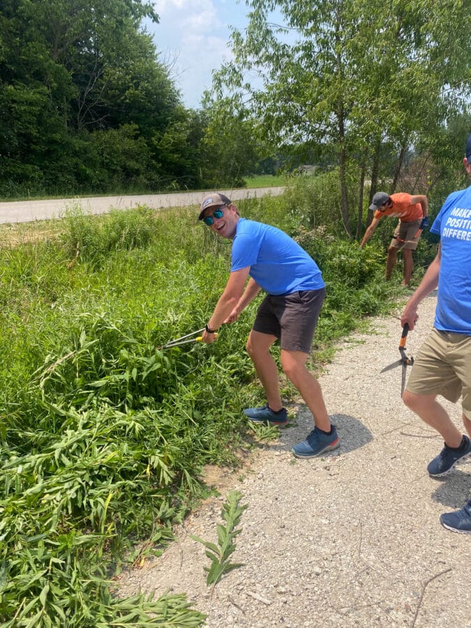 A DISHER Talent staff member volunteers by clearing brush along a path