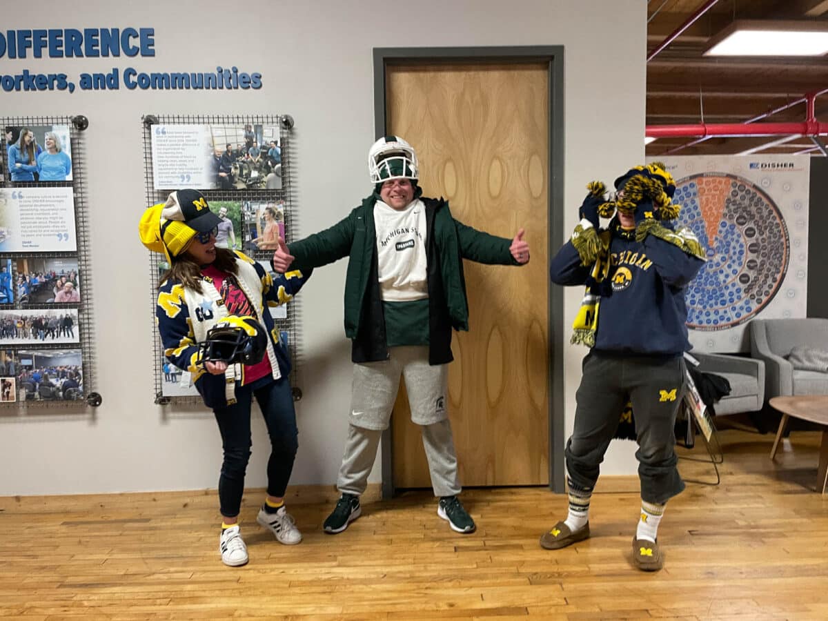 Three DISHER team members are dressed head to toe in collegiate gear