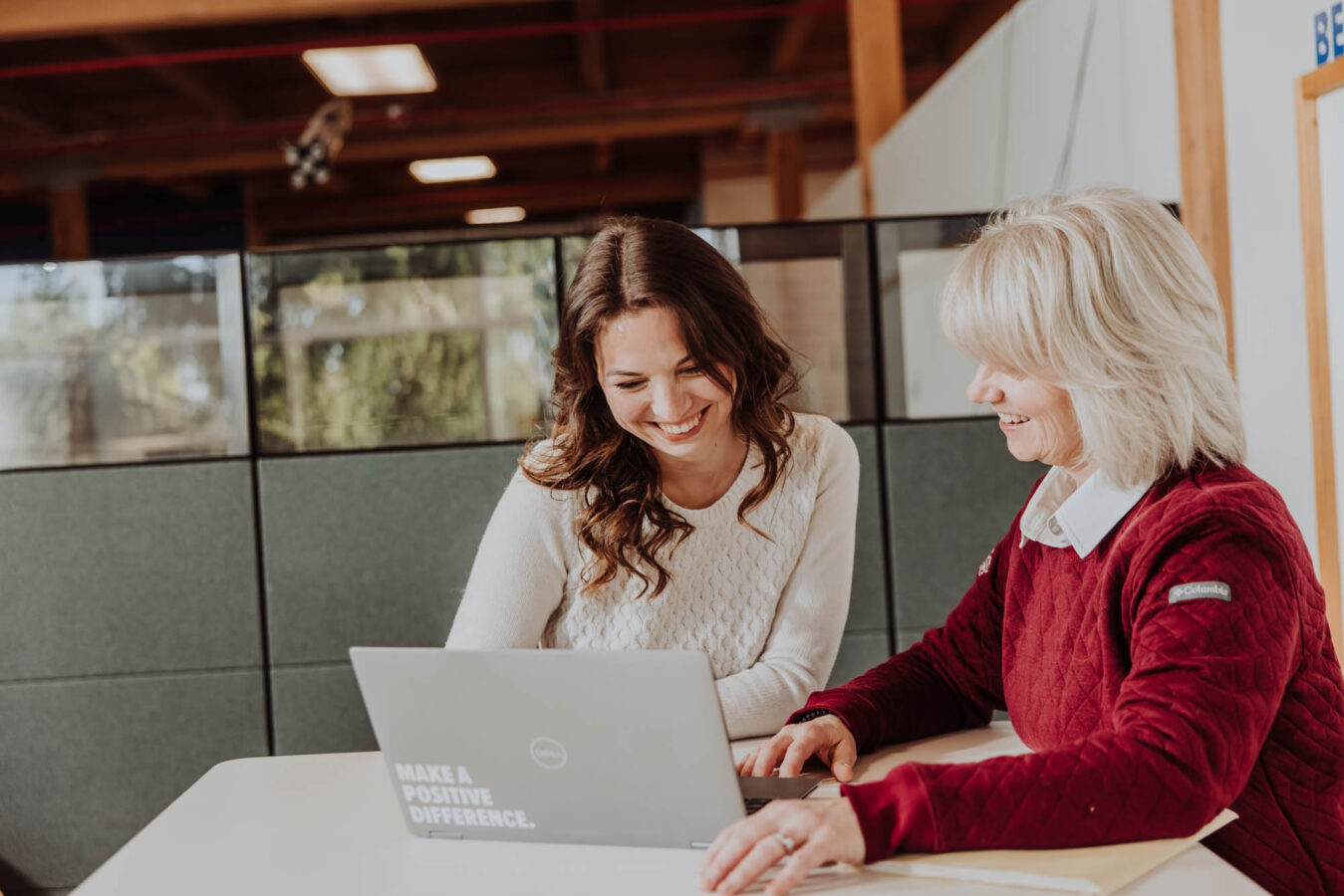 Two DISHER Talent Recruiters look at a computer together and smile