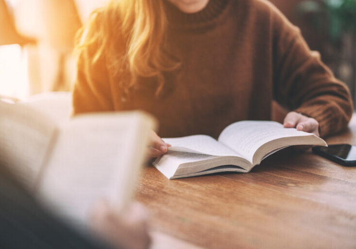 Two people sit at a table reading books