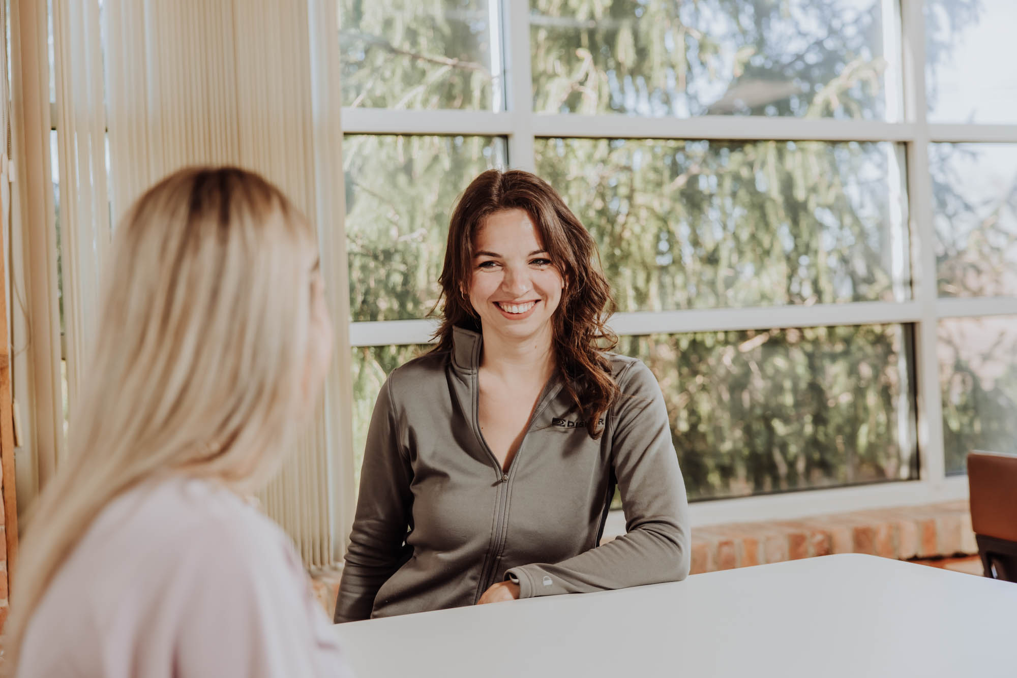 A recruiter sits at a table smiling at another woman
