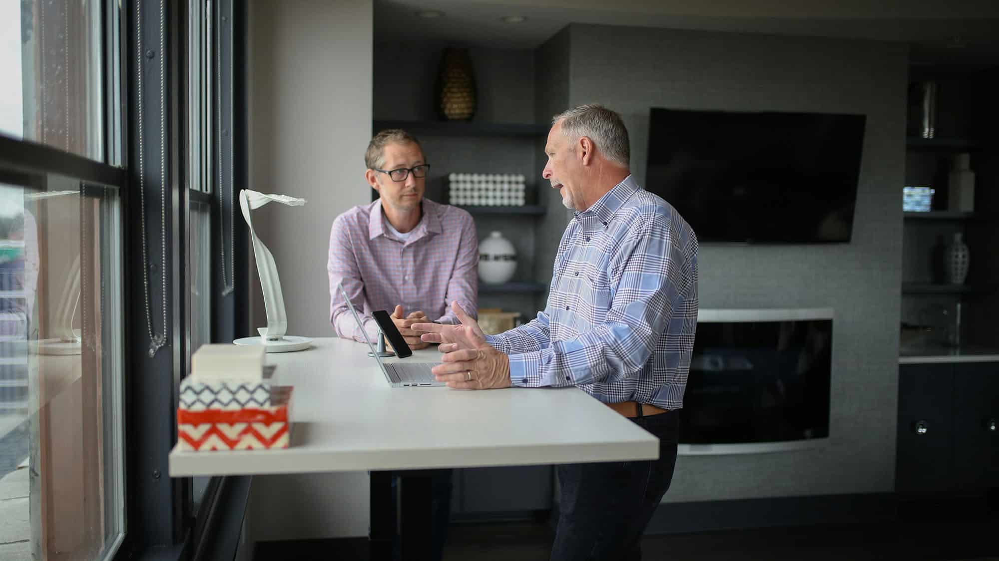 Two colleagues talking at a standing desk in a modern office