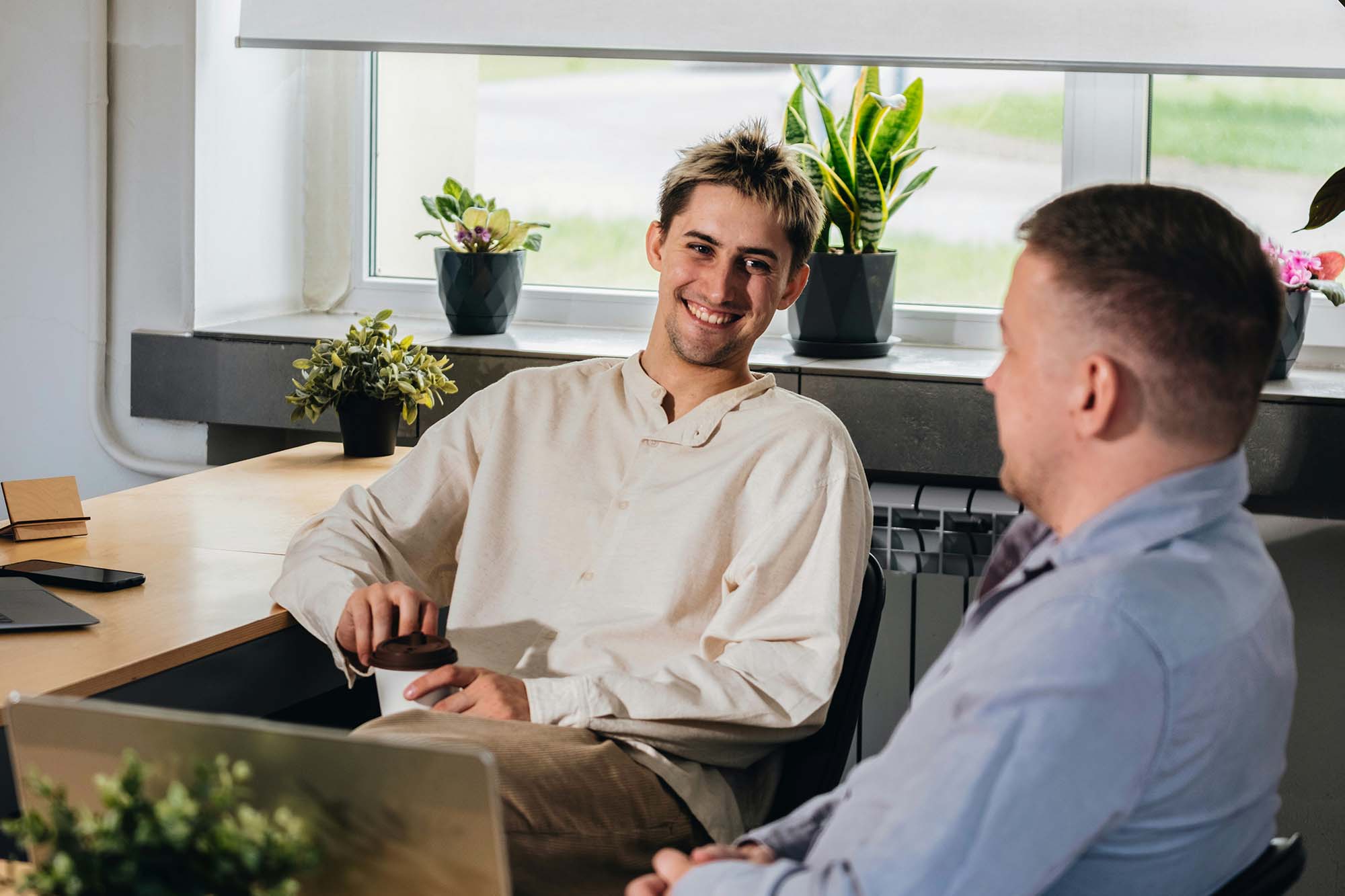 Two colleagues talking across a desk in a bright office during a meeting