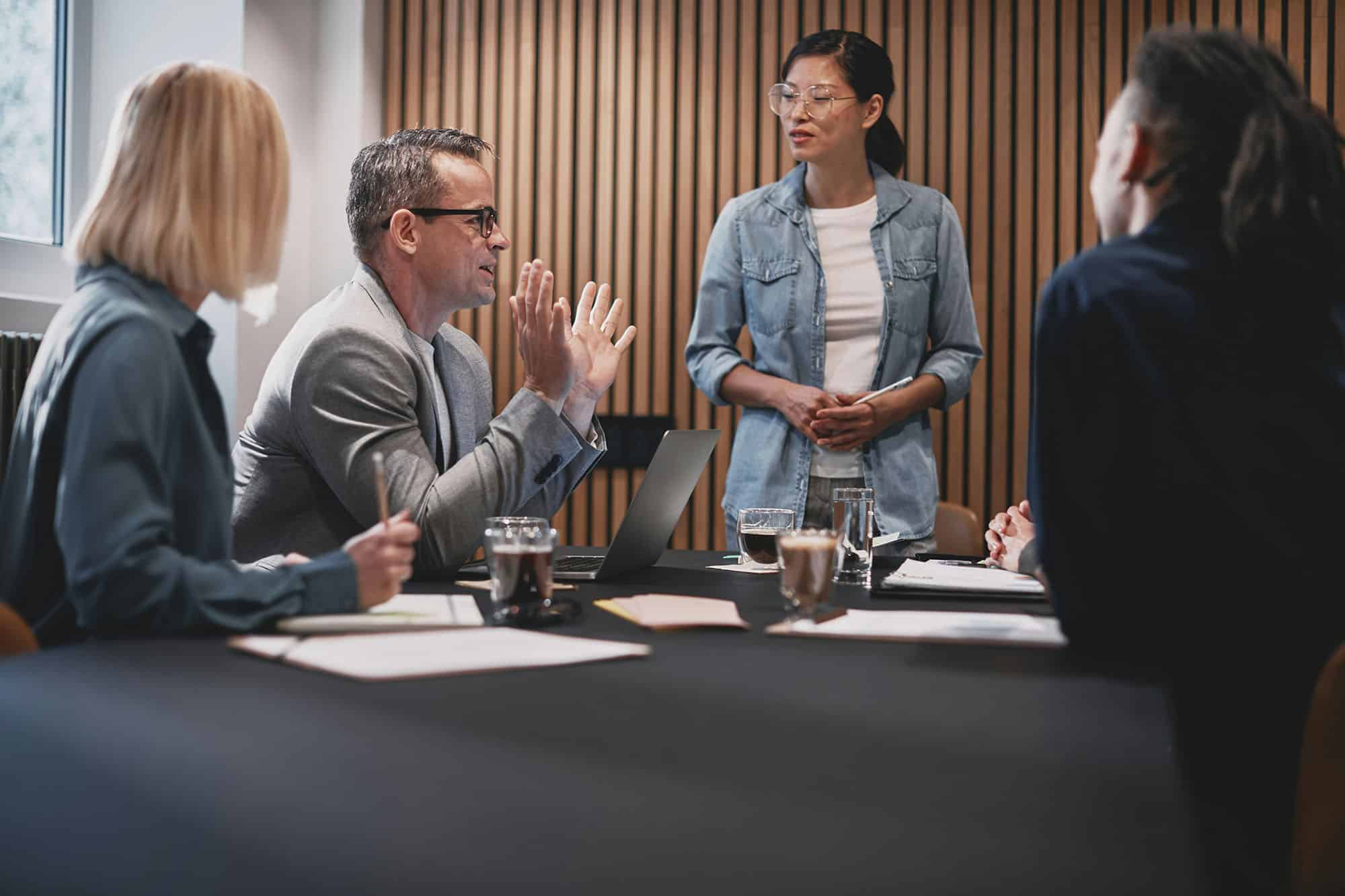 Colleagues discussing work around a conference table in a meeting room